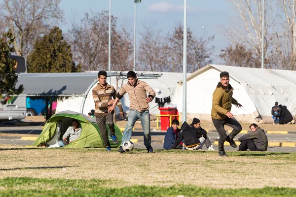 Migrantes e refugiados jogam futebol no estacionamento de um gás — Fotografia de Stock