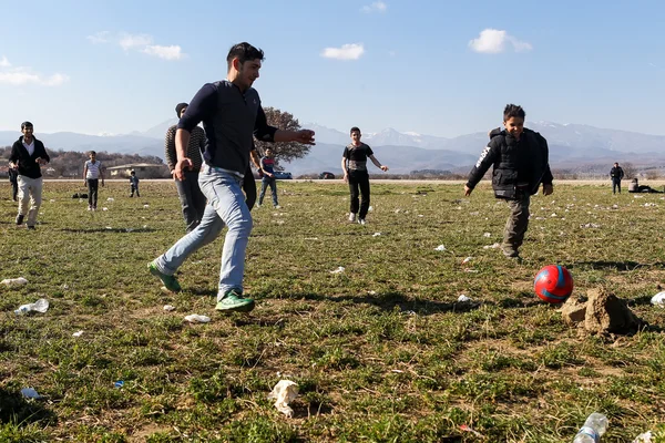 Migrants and refugees play football in the parking lot of a gas — Stock Photo, Image