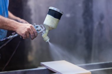 Ahşap tahta boyama boya tabancası ile protecti giyen adam işçi