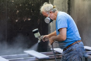 Ahşap tahta boyama boya tabancası ile protecti giyen adam işçi