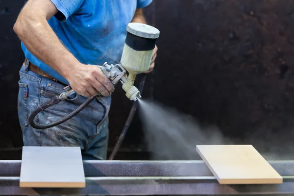 Homem trabalhador pintura placa de madeira com pistola de pulverização usando protecti — Fotografia de Stock