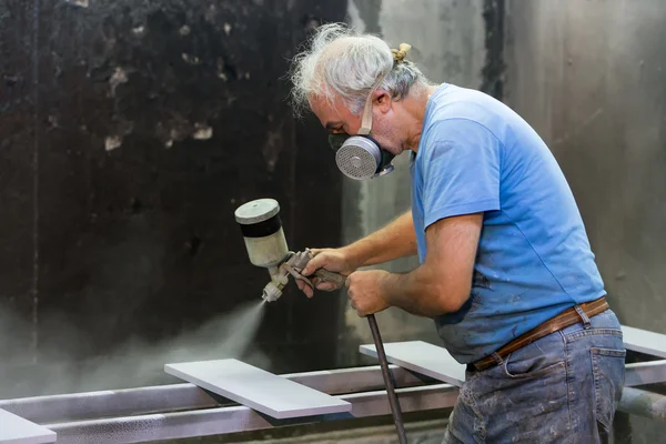 Homem trabalhador pintura placa de madeira com pistola de pulverização usando protecti — Fotografia de Stock