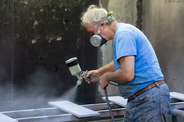 Homem trabalhador pintura placa de madeira com pistola de pulverização usando protecti — Fotografia de Stock