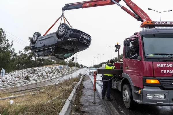 Un homme remorque une voiture endommagée sur une dépanneuse sur le bord de la route — Photo