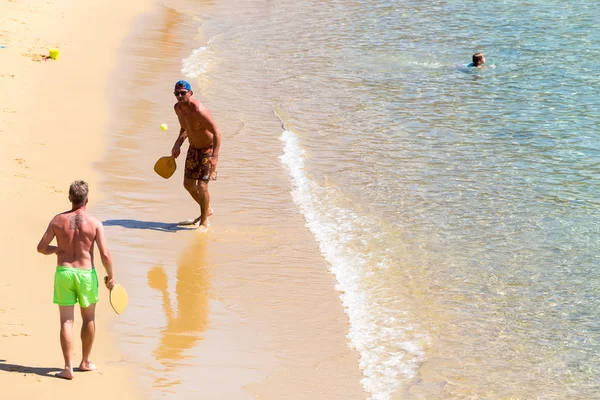 Tourists playing racket ball at the beach of Ios Greek island, i — Stock Photo, Image