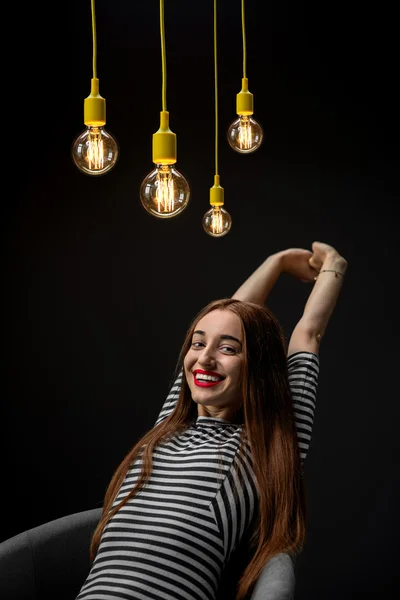 Jonge vrouw op de stoel met gele verlichte lampen — Stockfoto