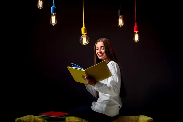 Ung kreativ student med färgglada lampor och böcker — Stockfoto