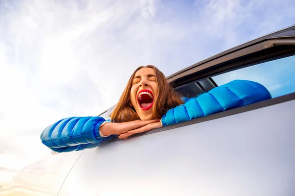 Женщина зевает, глядя в окно машины — стоковое фото
