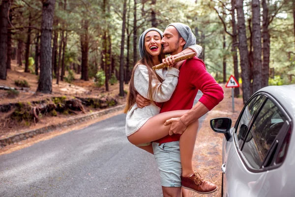 Young couple traveling by car in the forest — Stock Photo, Image