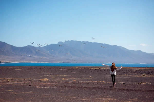 Беззаботная женщина бежит на пустынном фоне — стоковое фото