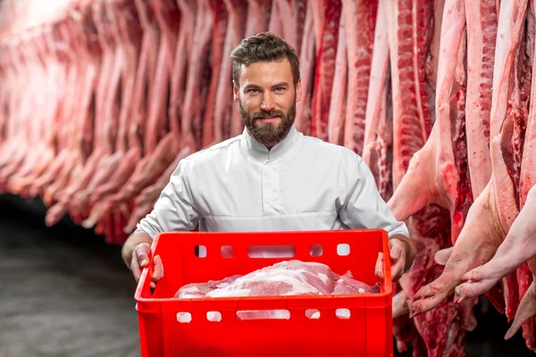 Açougueiro segurando caixa vermelha cheia com carne de porco crua — Fotografia de Stock