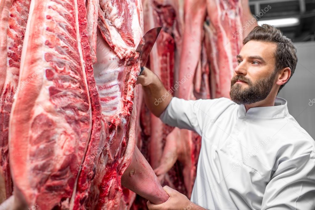 Butcher cutting pork at the manufacturing