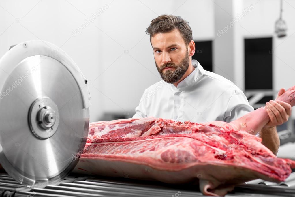 Butcher cutting meat at the manufacturing