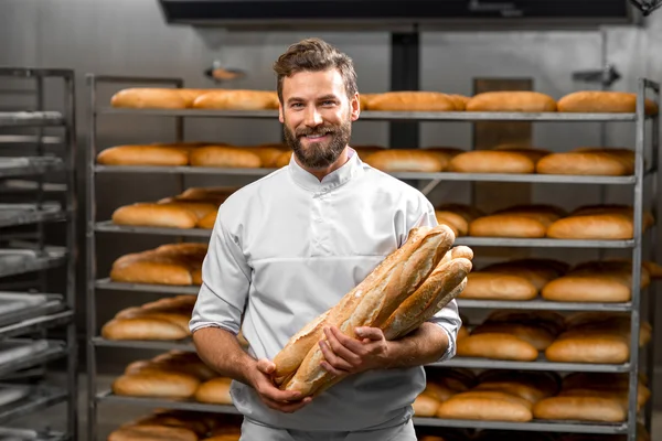 Bäcker hält Baguette in der Manufaktur — Stockfoto