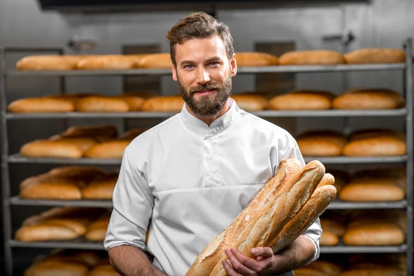 Panettiere che tiene baguette alla fabbricazione — Foto Stock