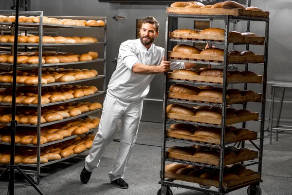 Trabalhador transportando prateleiras com pão — Fotografia de Stock