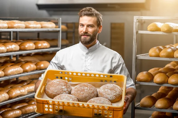 Padeiro segurando pães na fabricação — Fotografia de Stock