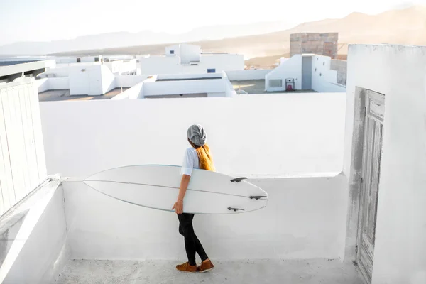 Γυναίκα με σανίδα του σερφ με λευκή πόλη παρασκήνιο — Φωτογραφία Αρχείου