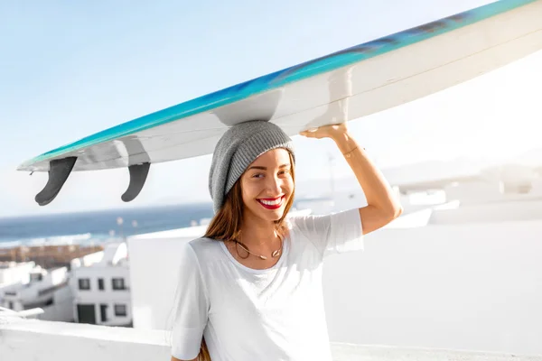 Жінка з дошкою для серфінгу на фоні білого міста — стокове фото