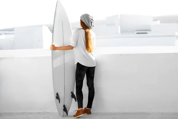 Frau mit Surfbrett auf weißem Stadthintergrund — Stockfoto