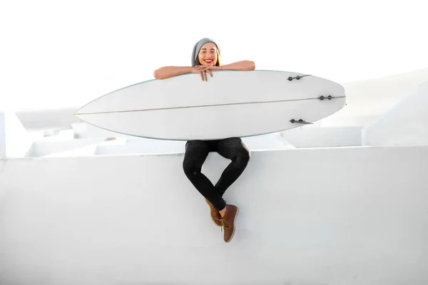 白い街背景にサーフボードを抱えて女性 — ストック写真