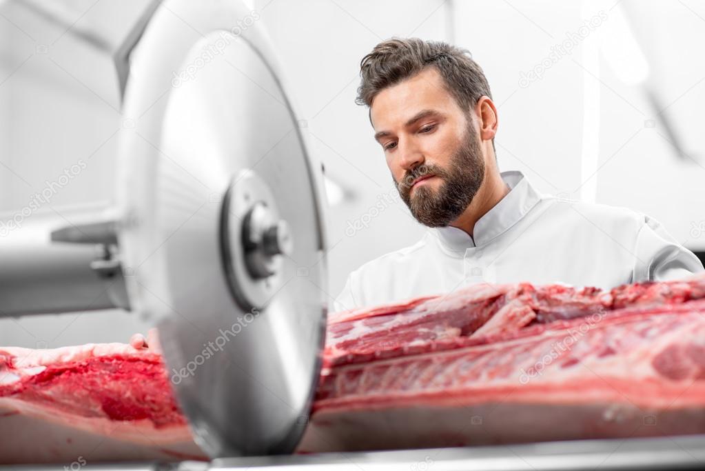 Butcher cutting meat at the manufacturing