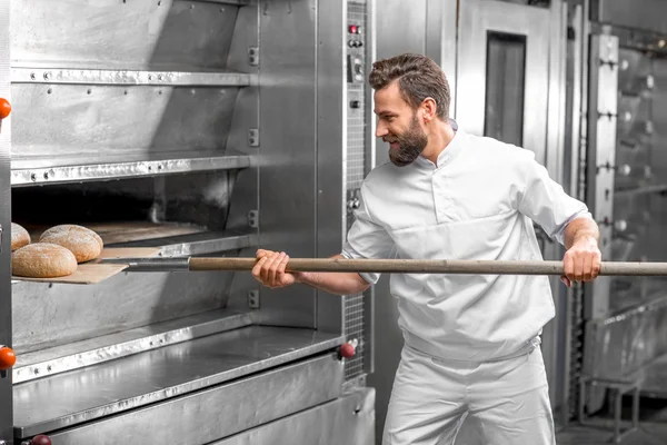 Пекарь вынимает из духовки хлеб из гречки — стоковое фото