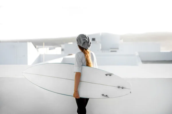 Mujer con tabla de surf en el fondo blanco de la ciudad — Foto de Stock