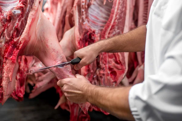 Мясник режет свинину на производстве — стоковое фото