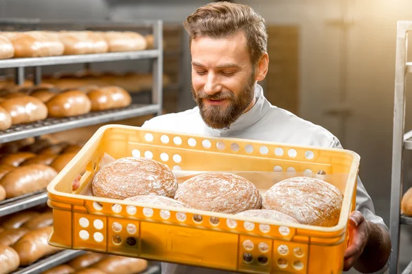 Padeiro segurando pães na fabricação — Fotografia de Stock