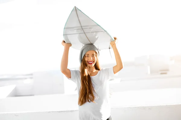 Frau mit Surfbrett auf weißem Stadthintergrund — Stockfoto