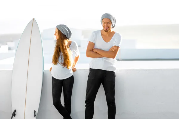 Casal com prancha de surf ao ar livre no fundo branco — Fotografia de Stock