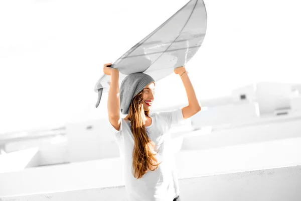 Woman with surfboard on the white city background — Stock Photo, Image