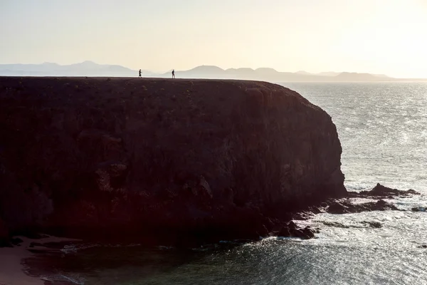 Rocha costeira enorme com silhueta de pessoas pequenas — Fotografia de Stock