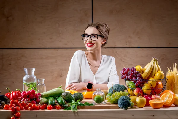 Mujer joven con frutas y verduras en la cocina — Foto de Stock