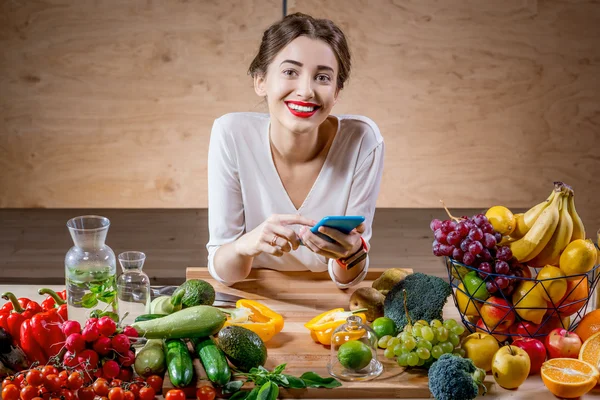 Молодая женщина с фруктами и овощами на кухне — стоковое фото