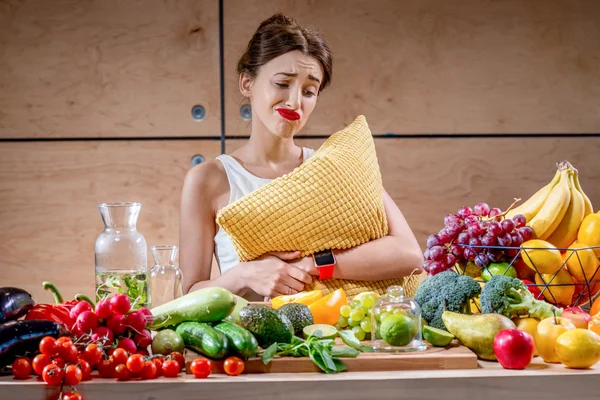 Mujer triste con almohada mirando en la comida — Foto de Stock