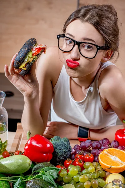 Mulher escolhendo entre fast food e legumes saudáveis, frutas — Fotografia de Stock