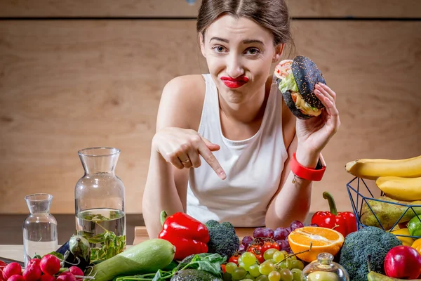 Женщина выбирает между фаст-фудом и здоровыми овощами, фруктами — стоковое фото