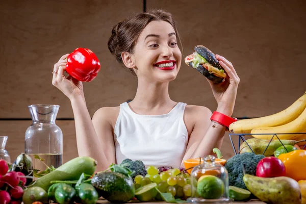 Mulher escolhendo entre fast food e legumes saudáveis, frutas — Fotografia de Stock