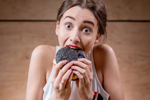 Woman eating black burger — Stock fotografie