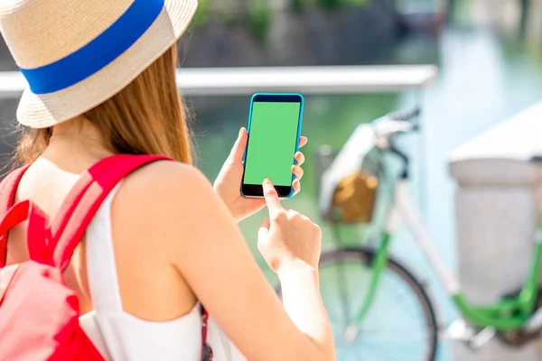 Vrouwelijke reiziger houden telefoon met groen scherm buitenshuis — Stockfoto