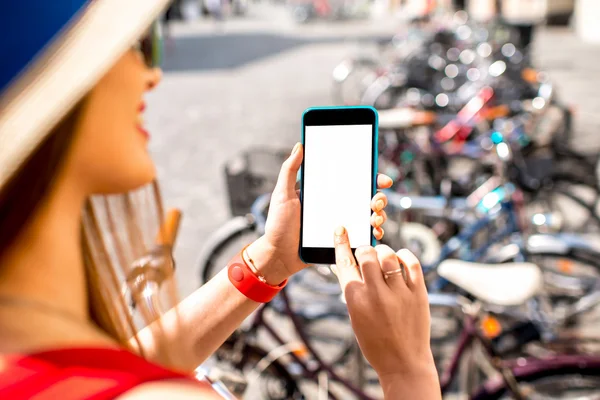 Woman renting a bicycle with smart phone — Stockfoto