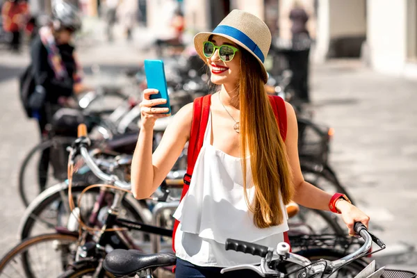 Mulher alugando uma bicicleta com telefone inteligente — Fotografia de Stock