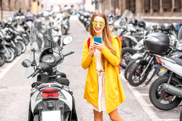 Mujer usando teléfono en la calle con scooters — Foto de Stock