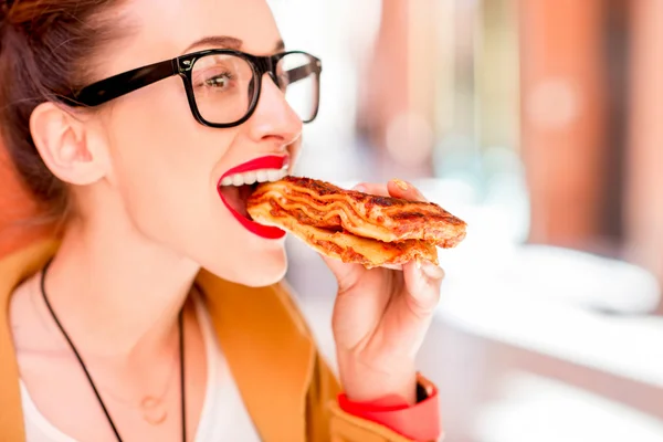 Žena jíst lasagne venku — Stock fotografie