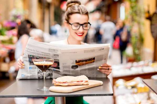 Žena čte noviny na venkovní kavárna — Stock fotografie