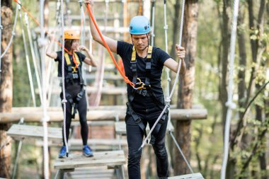Kadın ve erkek parktaki iplere tırmanıyor.