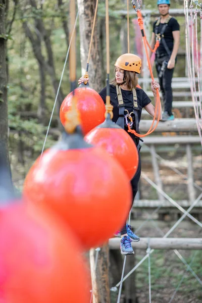 Kadın ve erkek parktaki iplere tırmanıyor.