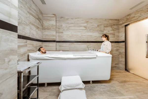 Homme avec un médecin à la salle de balnéologie avec bain de dioxyde de carbone — Photo